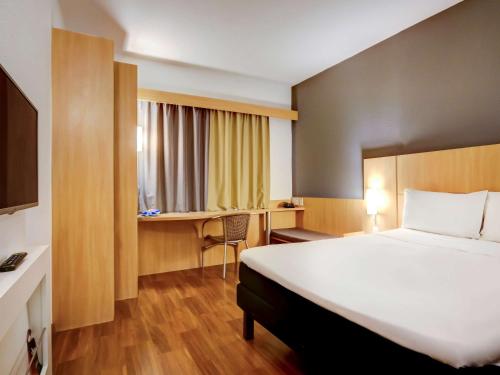 维多利亚维多利亚普拉亚多康拓宜必思酒店的酒店客房设有一张大床和一张书桌。