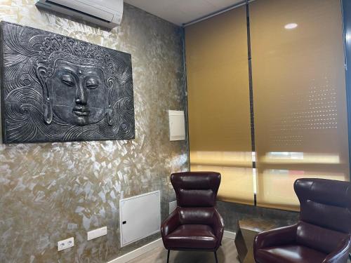 罗萨里奥港Espacio Room Fuerteventura的一间设有两把椅子和一面墙上面具的等候室