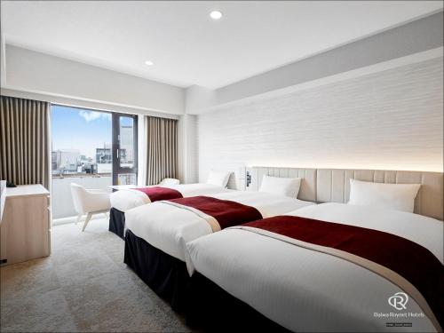 仙台Daiwa Roynet Hotel Sendai Nishiguchi PREMIER的酒店客房设有三张床和窗户。