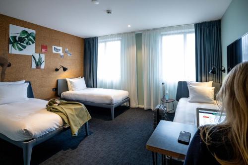 阿姆斯特丹Conscious Hotel Amsterdam City - The Tire Station的坐在旅馆房间,带两张床的女人