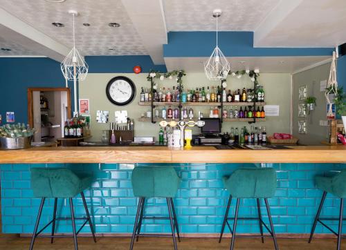 德拉姆纳德罗希特Loch Ness Drumnadrochit Hotel的一间酒吧,拥有蓝色的墙壁和酒吧凳子