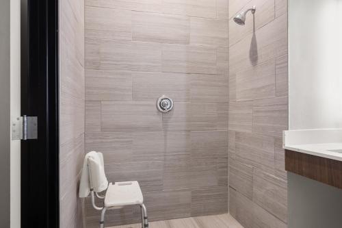 Graham格雷厄姆智选假日宾馆的浴室内配有带白色椅子的淋浴