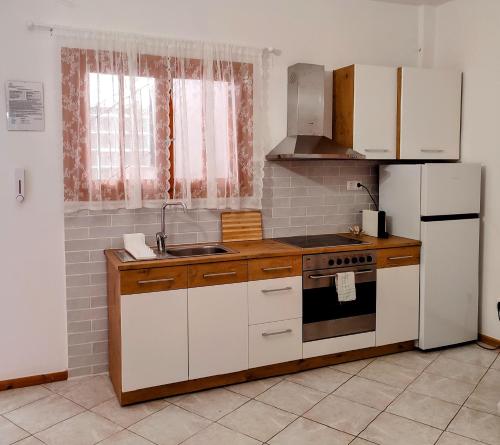 瓦西Maroudas Stavros Apartments的厨房配有白色橱柜、炉灶和冰箱。