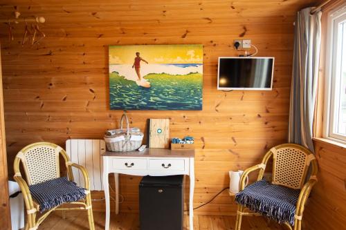 纽基Tolcarne Beach Cabins的一间带两把椅子、一张桌子和一台电视的房间