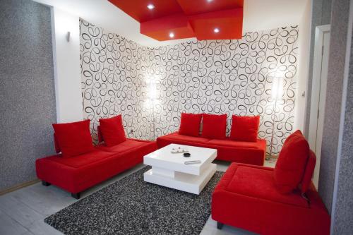 贝尔格莱德红公寓的客厅配有红色沙发和白色桌子