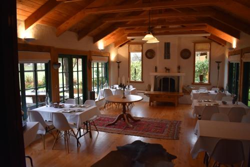 奥阿库尼河畔旅馆的一间带桌椅和壁炉的用餐室