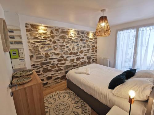 布格奈斯L'Escale - Les Maisons de Madeleine的一间卧室设有一张大床和石墙
