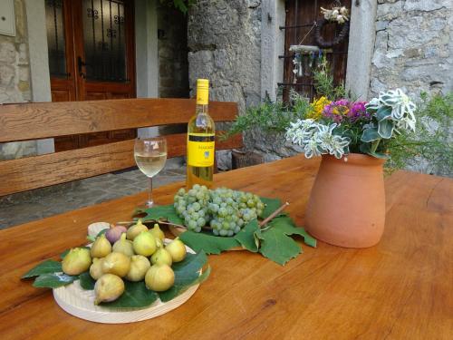 Pri kovačih, Istra autentica的木桌旁的一瓶葡萄酒和一碗水果