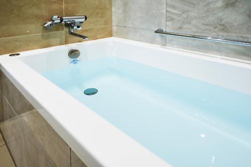 盛冈Daiwa Roynet Hotel Morioka Ekimae的浴室内设有带水龙头的白色浴缸