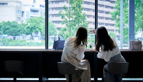 盛冈Daiwa Roynet Hotel Morioka Ekimae的两个女人坐在柜台上,看着窗外