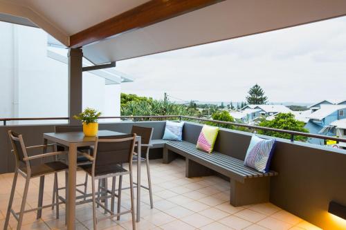 科夫斯港Coffs Jetty Beach House的阳台配有长凳和桌椅。