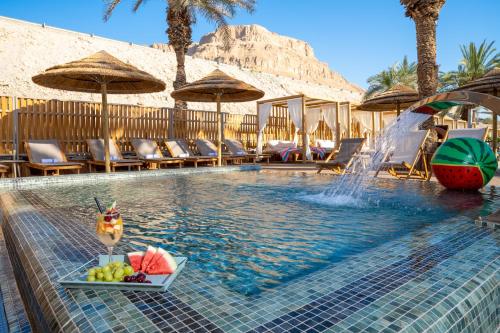 恩波其克Oasis Spa Club Dead Sea Hotel - 18 Plus的游泳池,有一碗水果和喷泉