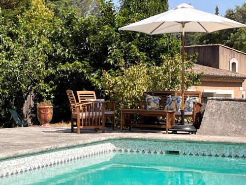 尼姆Chambre indépendante avec terrasse privée et piscine的一个带遮阳伞和桌椅的游泳池