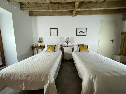 TrocheDordogne et Corrèze vacances BnB的配有白色床单和黄色枕头的客房内的两张床