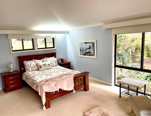谭伯连山Tamborine Mountain Lodge的一间卧室设有一张床和一个大窗户