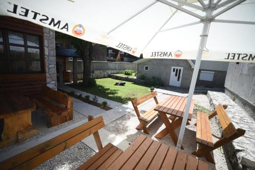 扎布利亚克Cabarkapa Guesthouse的庭院设有2个木制长椅和遮阳伞