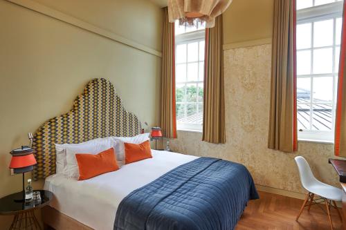 埃克塞特埃克塞特红酒酒店的一间卧室配有带橙色枕头的床和窗户。