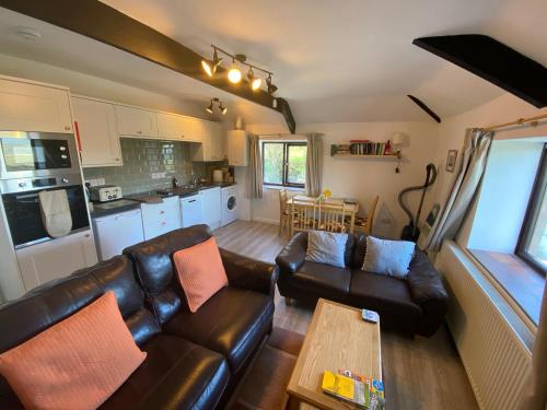 博斯卡斯尔Polrunny Farm Elderberry Cottage with sea view的客厅配有真皮沙发和桌子