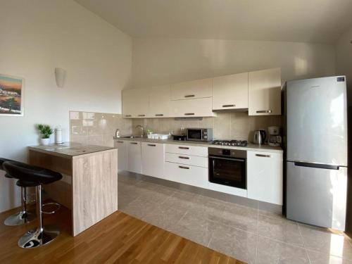 马卡尔斯卡apartman Ivan的厨房配有白色橱柜和不锈钢冰箱