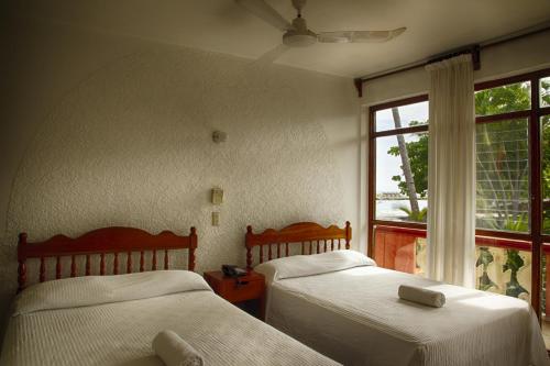 埃斯孔迪多港Rincon del Pacifico的带窗户的客房内的两张床