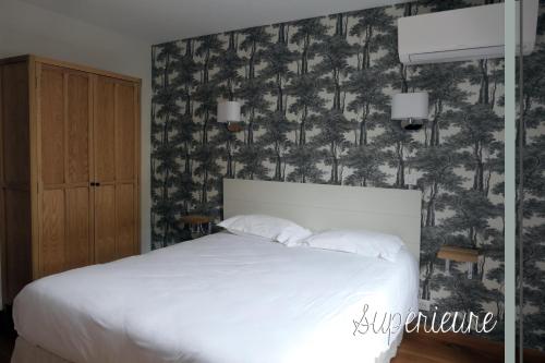 塞扎讷Logis Le Relais Champenois的一间卧室设有一张床,墙上有松树