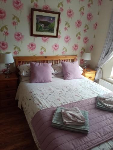 阿伯加文尼The Guest House的卧室配有一张墙壁上粉红色鲜花的床。