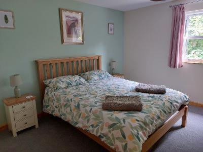 佩伦波斯Two bedroom cottage - country lane -10 min walk to Perranporth beach的一间卧室配有一张带木制床头板的床和一张四柱床。