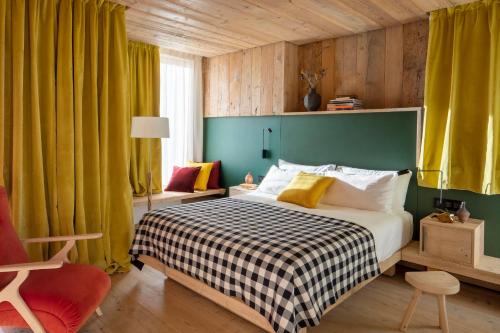 科尔蒂纳丹佩佐HOTEL de LEN的一间卧室配有一张带绿色墙壁和黄色窗帘的床