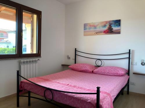 奥尔比亚Smeralda的一间卧室配有一张带粉色床单的床和一扇窗户。