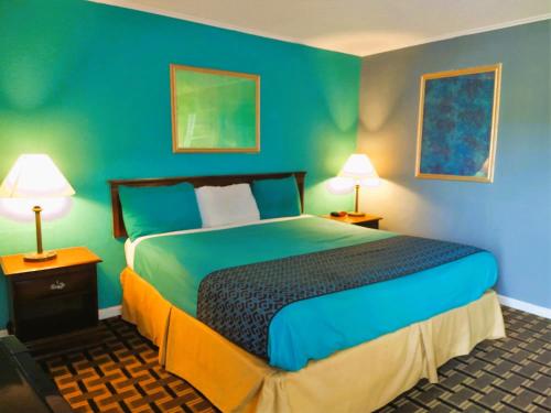 章克申城Grandview Plaza Inn的一间卧室配有一张蓝色墙壁的床和两盏灯。