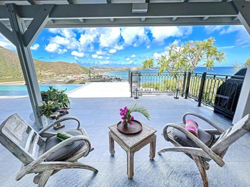 格兰德凯斯Frangipani Room in shared Villa Diamant, swimming pool, sea view的一个带两把椅子和一张桌子的庭院和大海
