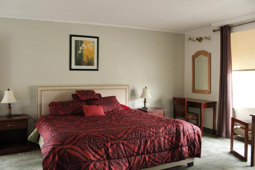 普尔曼American Travel Inn的一间卧室配有一张红色棉被的床