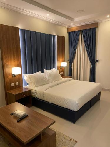布赖代Reef Al Qassim Hotel Apartments的一间卧室配有一张大床和一张茶几