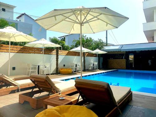 卡萨米尔Valmar Hotel的游泳池旁的游泳池配有椅子和遮阳伞
