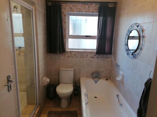 肯普顿帕克Inviting 3-Bed House in Kempton Park的一间带卫生间和浴缸的浴室以及窗户。