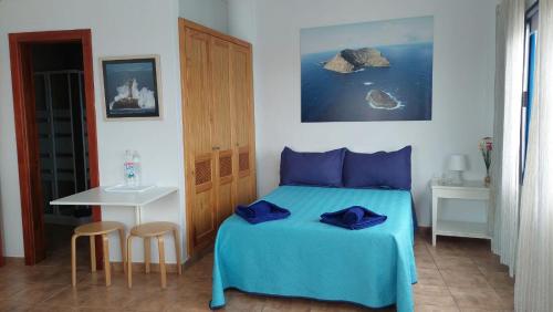 奥尔索拉APARTAMENTO ROQUE DEL ESTE的一间卧室配有一张带蓝色床单的床和一张桌子。