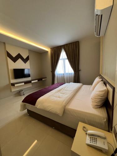 索哈尔Aalia Hotel Suites的一间卧室配有一张床和一张书桌及电话