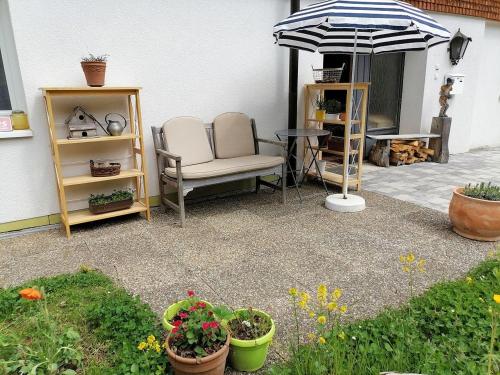 欣特察尔滕Ferienwohnung Heustüble的庭院配有两把椅子、一张桌子和一把遮阳伞