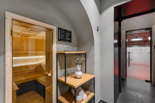 布达佩斯Hotel Oktogon Haggenmacher by Continental Group的浴室设有步入式淋浴间,书架上摆放着花瓶