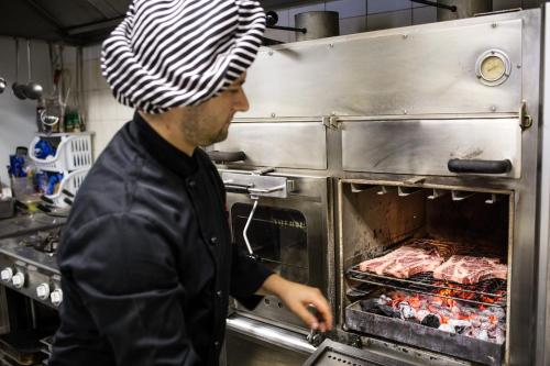 Preturo马萨里住宿加早餐旅馆的男人把肉放进烤箱里