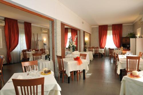 莫利内拉Hotel Mini Palace - Country House的一间设有白色桌椅和红色窗帘的餐厅