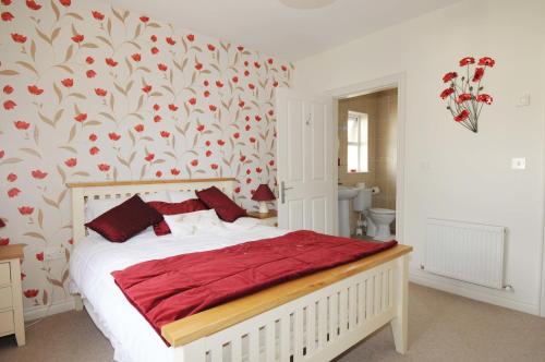 Derrylinslieve rushen的一间卧室配有一张带红色枕头的床和花卉壁纸