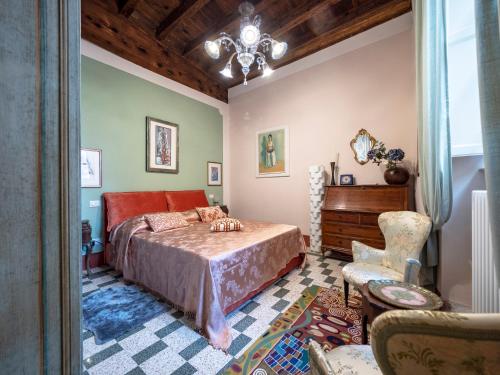 卢卡LUXURY - Elegante appartamento nel cuore di Lucca的一间卧室配有一张床、一把椅子和一个吊灯。