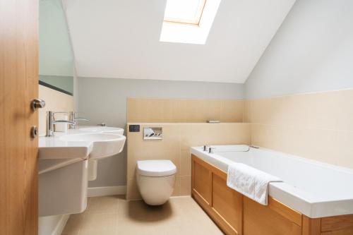 纽基Fistral hot tub house for 8 on Retallack Resort的带浴缸、卫生间和盥洗盆的浴室