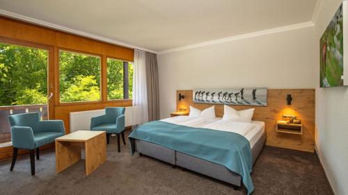因泽尔Das Wiesgauer - Alpenhotel Inzell的一间卧室配有一张床和两张蓝色椅子