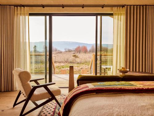 加德纳Wildflower Farms, Auberge Resorts Collection的卧室配有床、椅子和窗户。