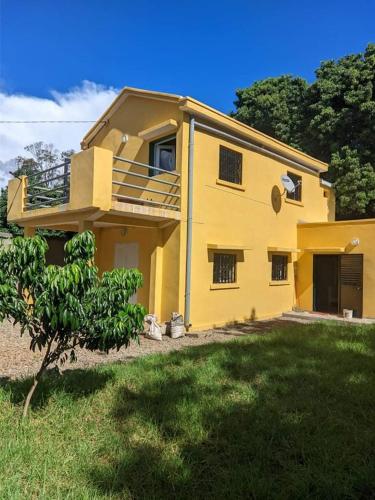 Villa Emma Ampefy的前面有一棵树的黄色房子