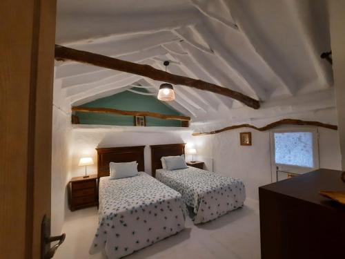 伊斯纳哈尔Casa Arroyo - Rosa & Nispero的一间带两张床的卧室和白色天花板
