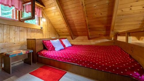 Stara SušicaChalet Woody的小木屋内的一张床位,配有红色棉被