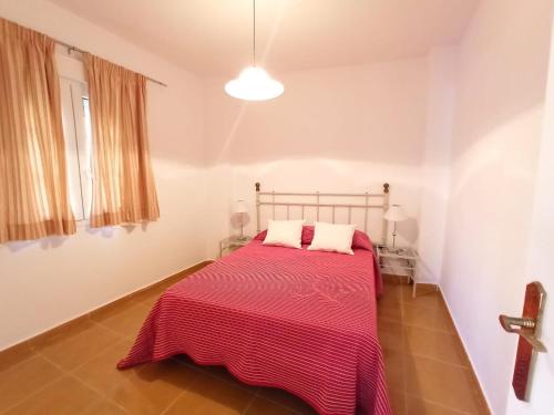 卡内拉岛Acogedor apartamento a 50 metros de la playa的一间卧室配有一张带红色毯子的床